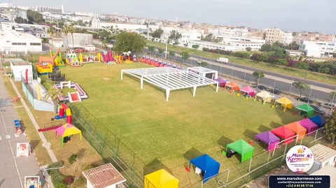 Vue aérienne du Kids Day Somaca : structures gonflables, stands colorés et chapiteau sur la pelouse de l'usine